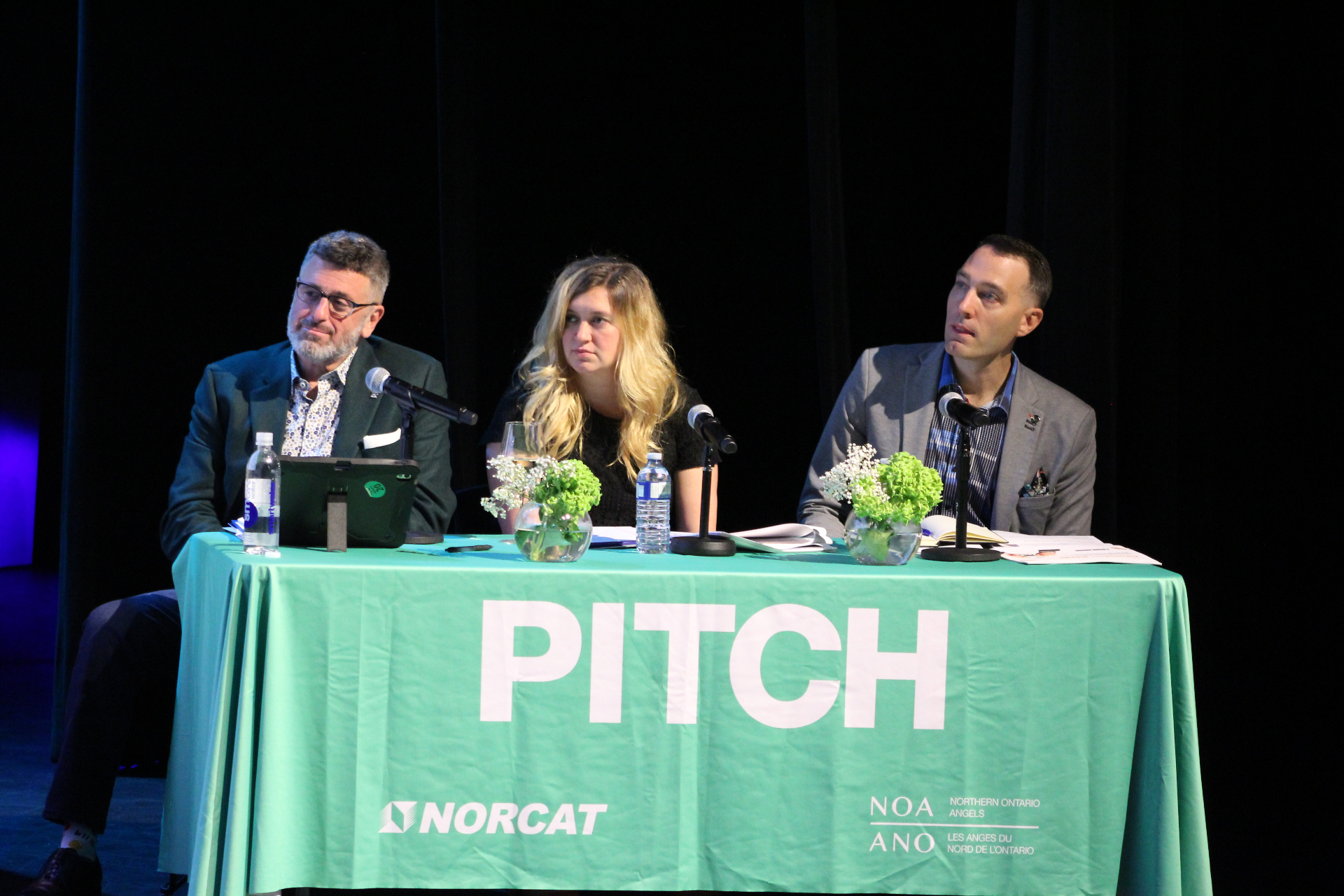 Speaker at the Venture North PITCH podium with Event Partner sponsor branding projected on stage.
